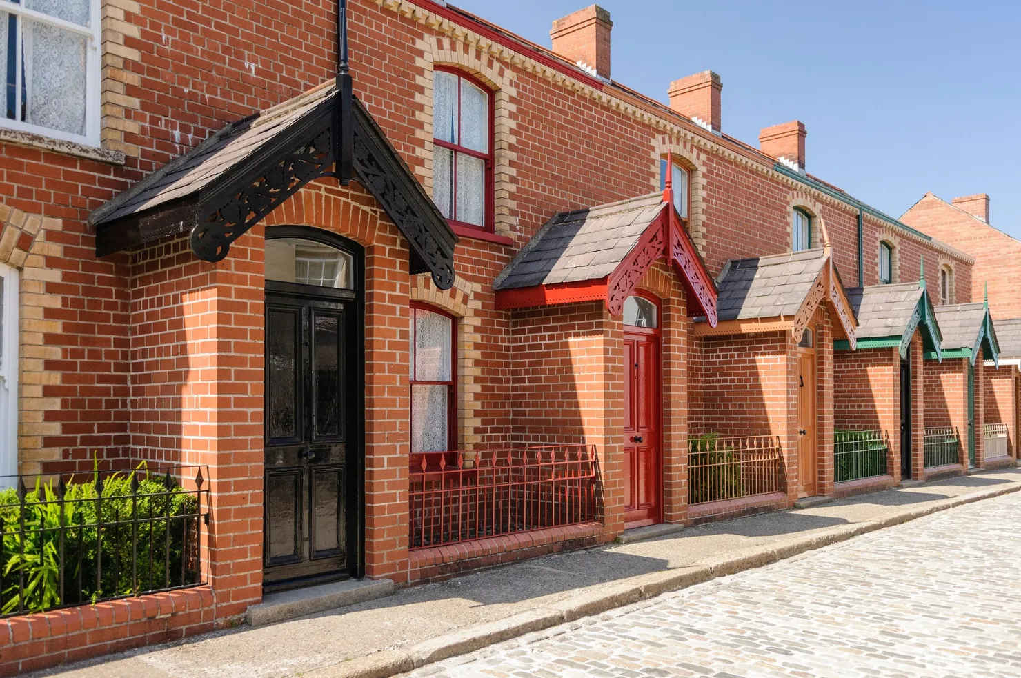 Victorian red-brick terraced houses with gabled porches along a cobbled street in Belfast