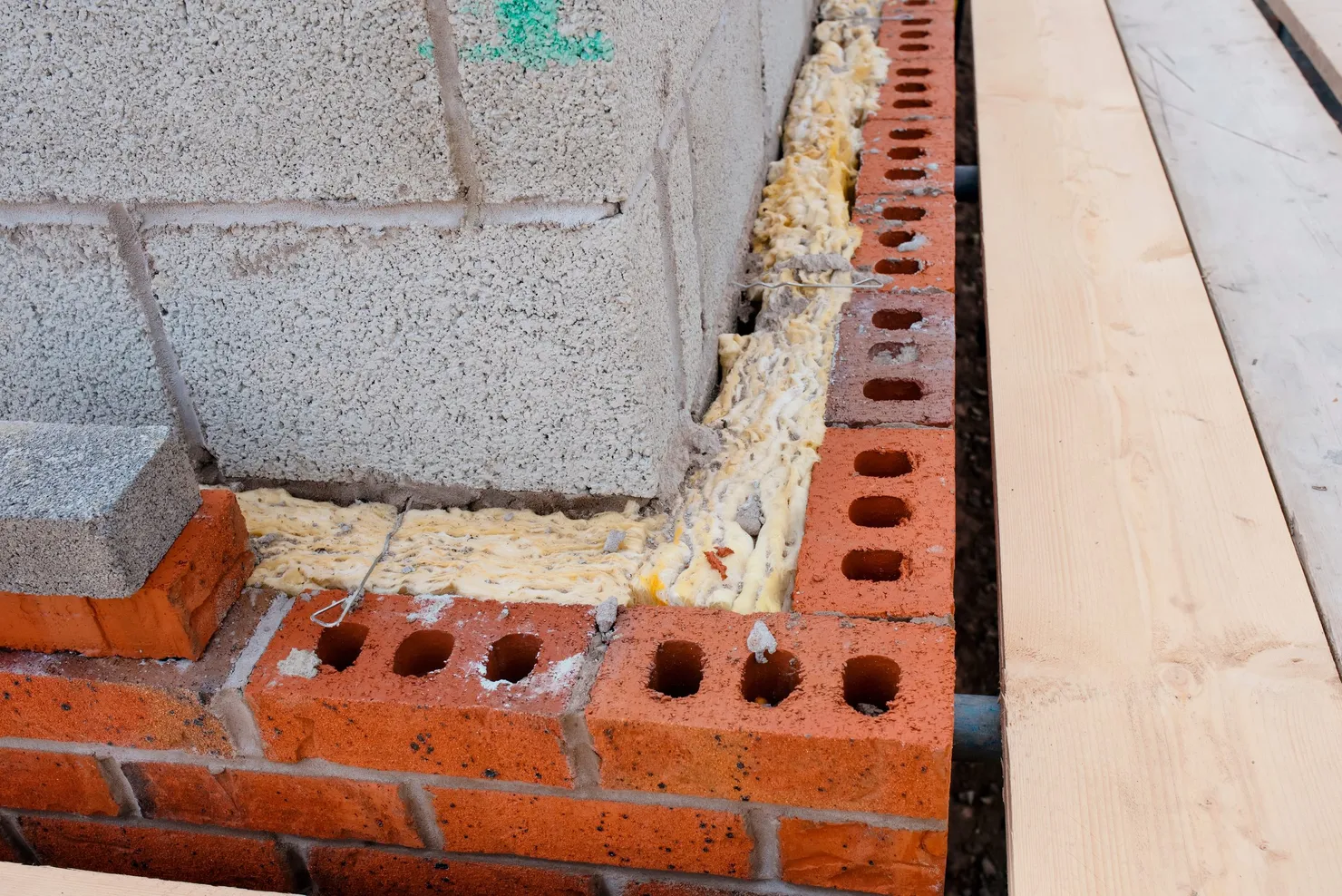 A brick and block wall under construction, with mineral wool insulation filling the cavity between the two leaves