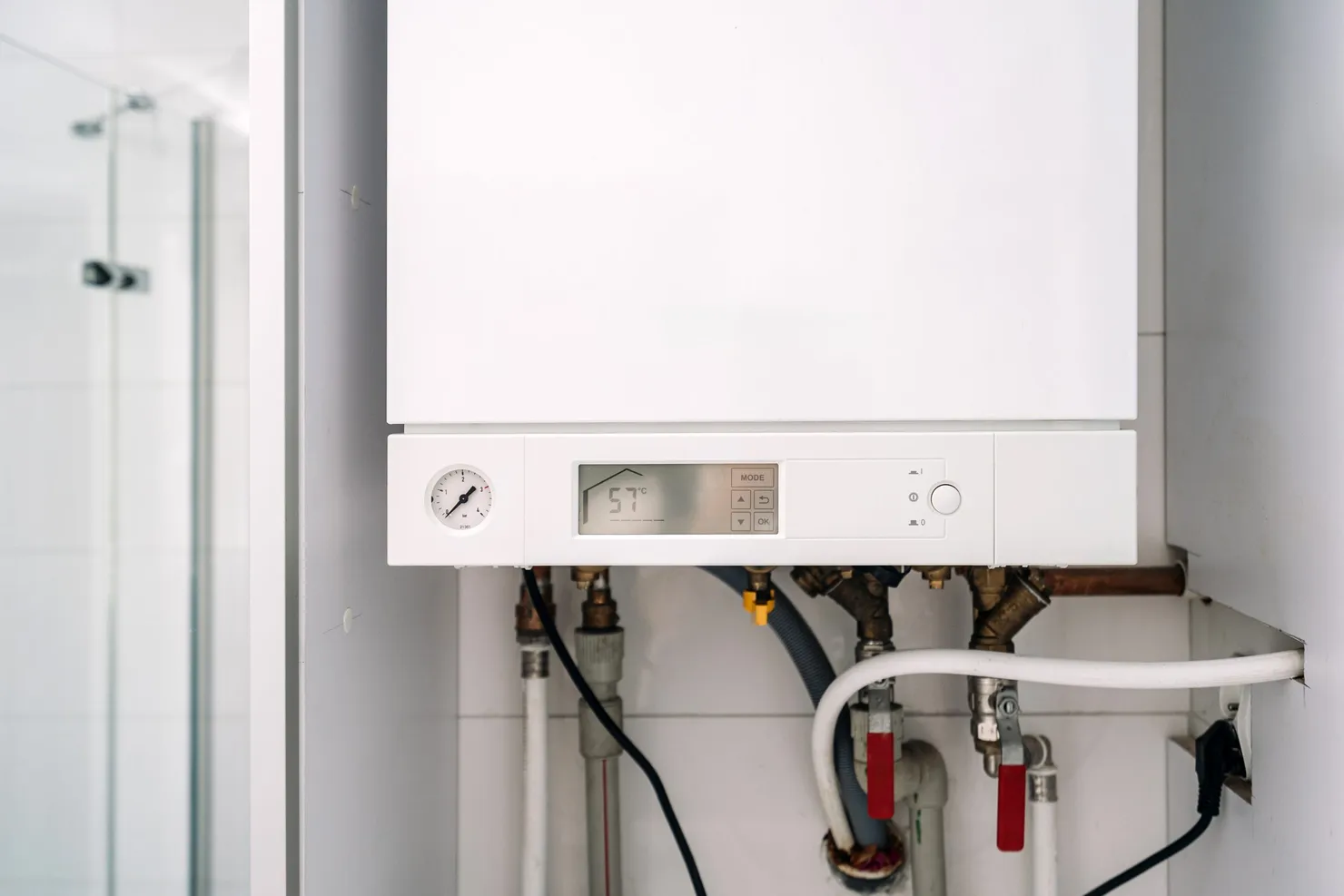 A wall-mounted gas boiler with its pressure gauge, controls and pipework beneath it