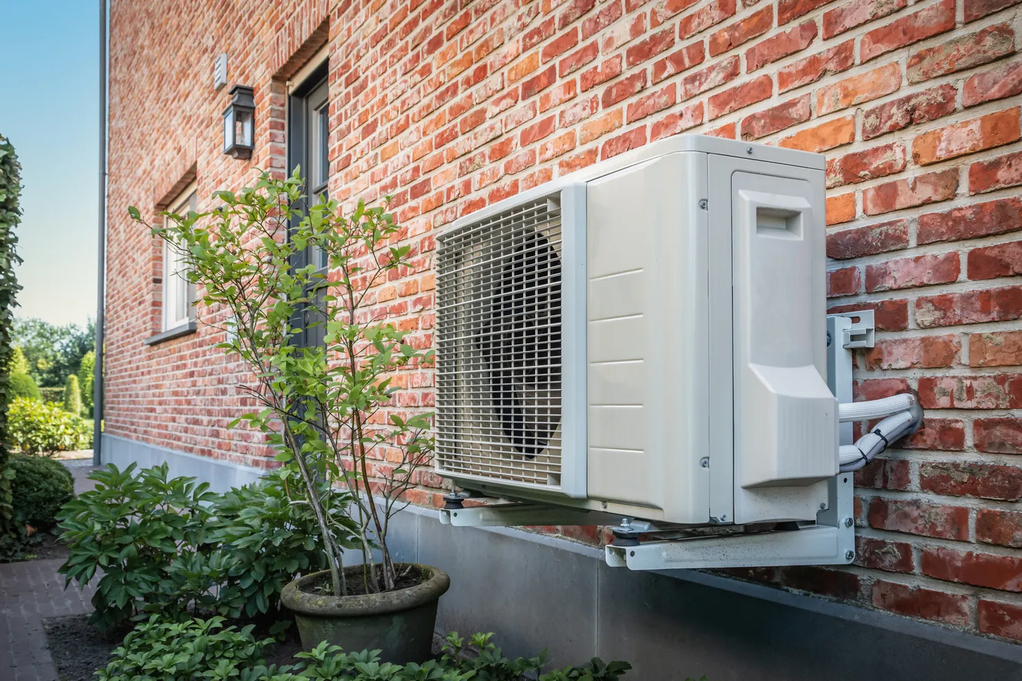 Air source heat pump unit mounted on the exterior brick wall of a UK home