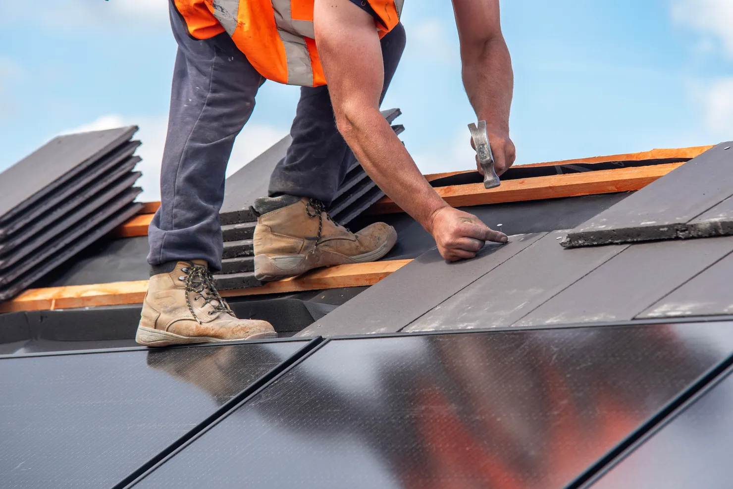 Roofer installing solar panels and roof tiles on a UK home