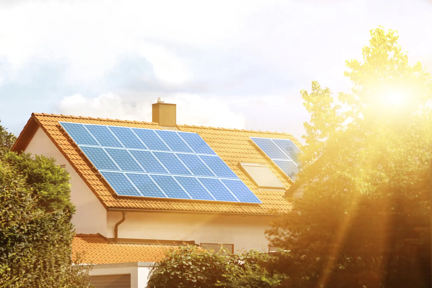 Solar PV panels mounted on the tiled roof of a UK home in bright sunlight