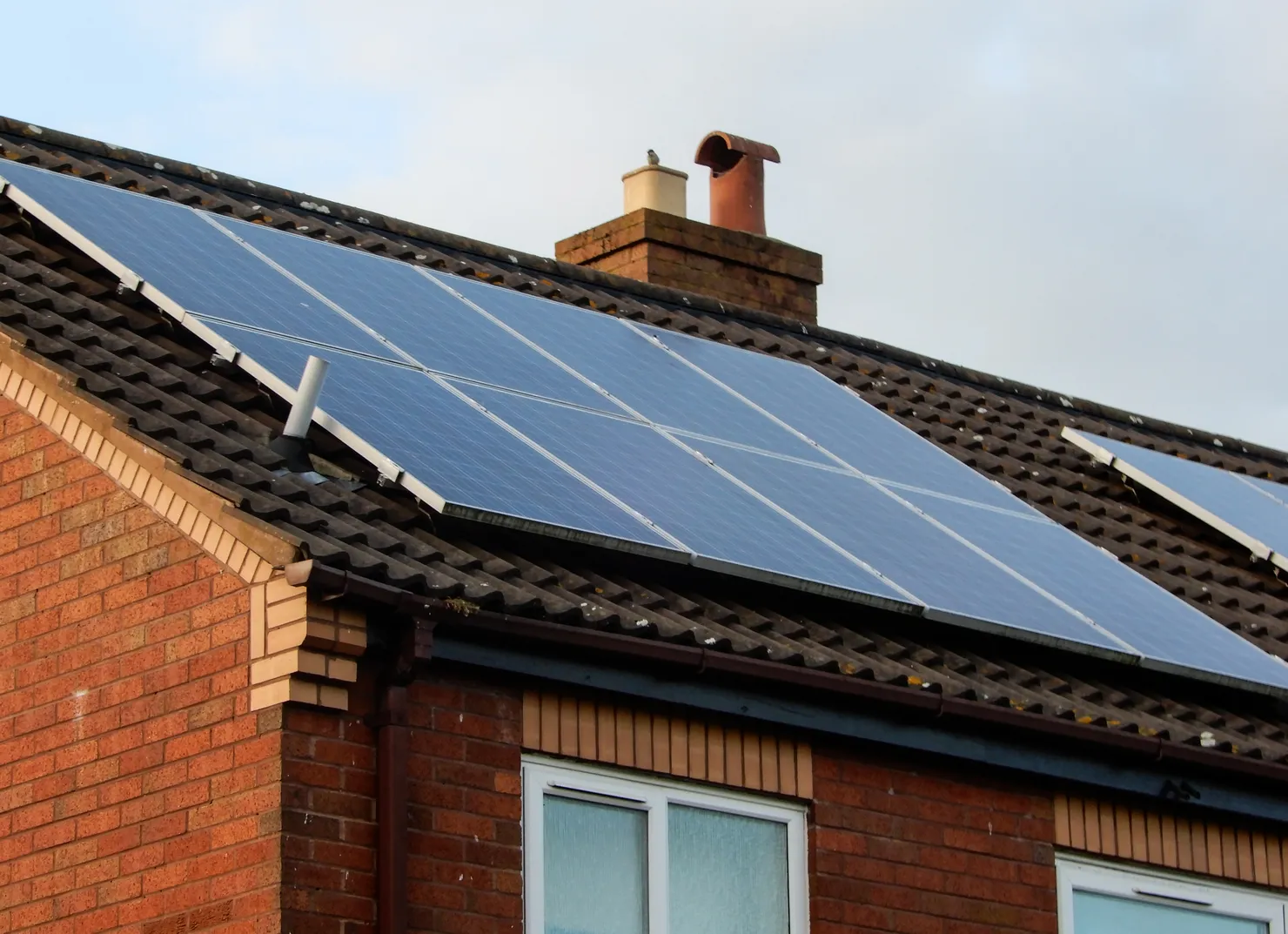 A full solar panel array across the pitched roof of a UK brick home